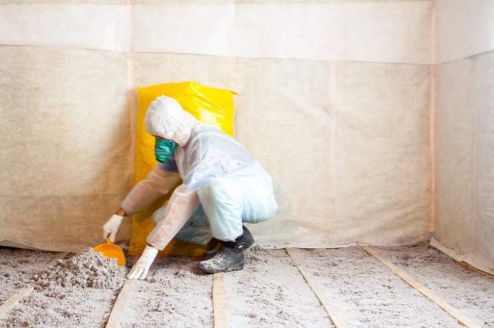 Artisan professionnel en pleine isolation de combles perdus, utilisant des équipements de protection et des matériaux isolants en vrac, lumière naturelle.